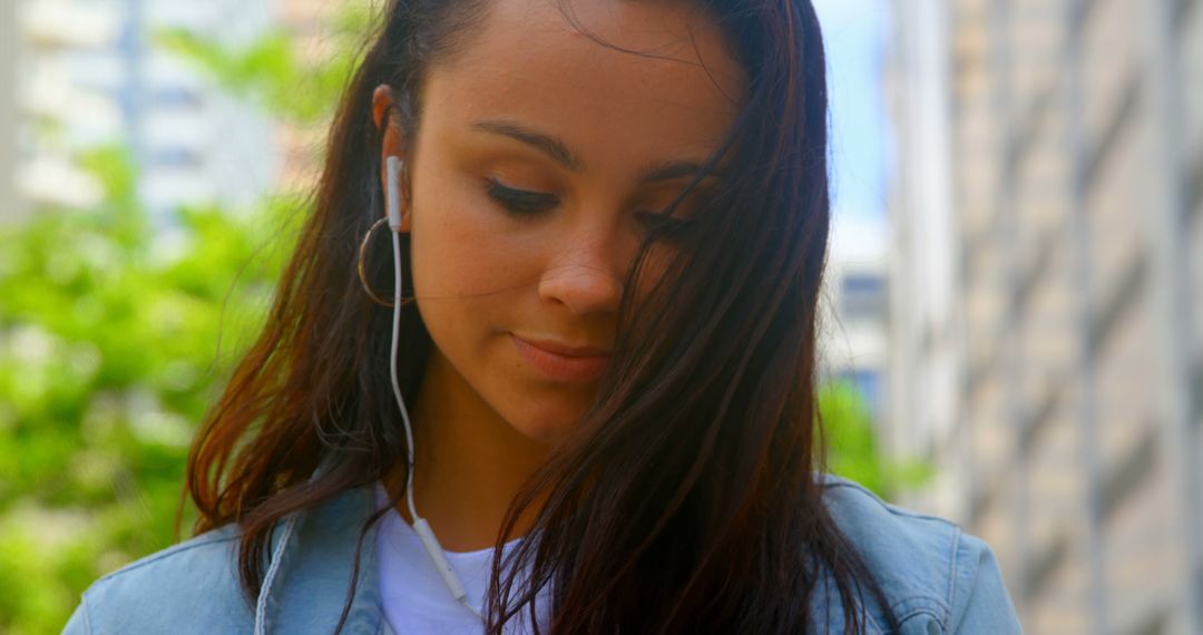 Young Woman Listening to Music on Earphones in Urban Environment - Free Images, Stock Photos and Pictures on Pikwizard.com