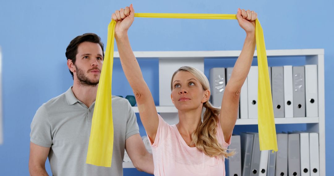 Physical Therapist Assisting Woman With Resistance Band Exercises in Office - Free Images, Stock Photos and Pictures on Pikwizard.com