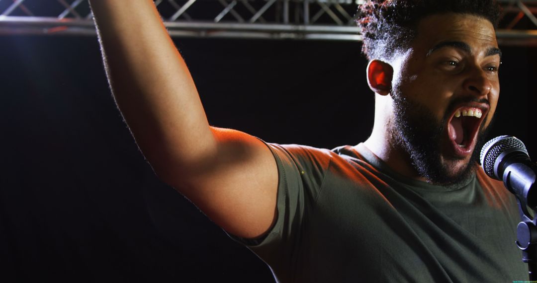 Diverse Man Singing Passionately on Stage with Microphone
