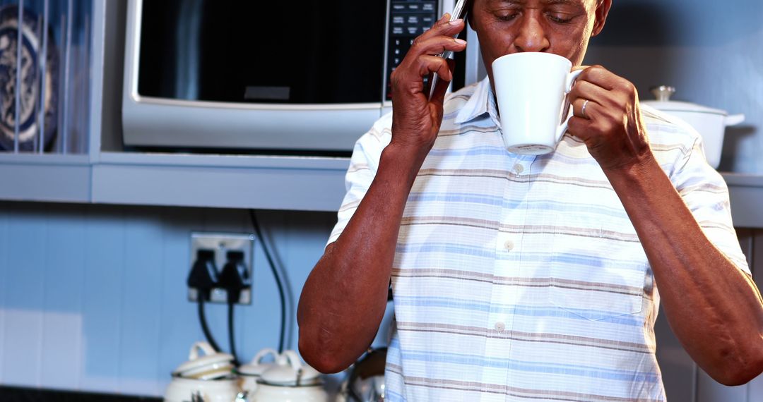 Elderly Man Drinking Coffee While Talking on Phone in Kitchen - Free Images, Stock Photos and Pictures on Pikwizard.com