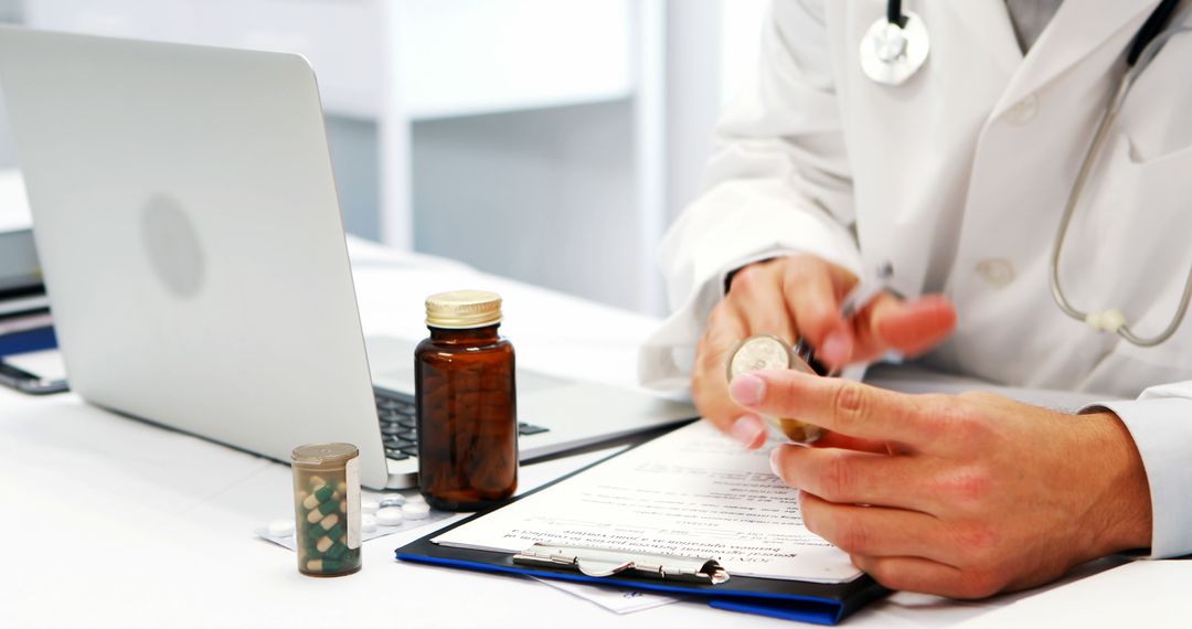 Doctor Analysing Patient's Prescription with Pills and Laptop on Desk - Free Images, Stock Photos and Pictures on Pikwizard.com