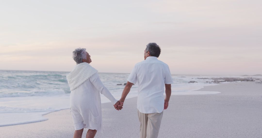 Senior Couple Walking Hand in Hand on Serene Sunset Beach