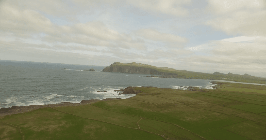 Scenic atlantic coastline meeting verdant fields under cloudy skies