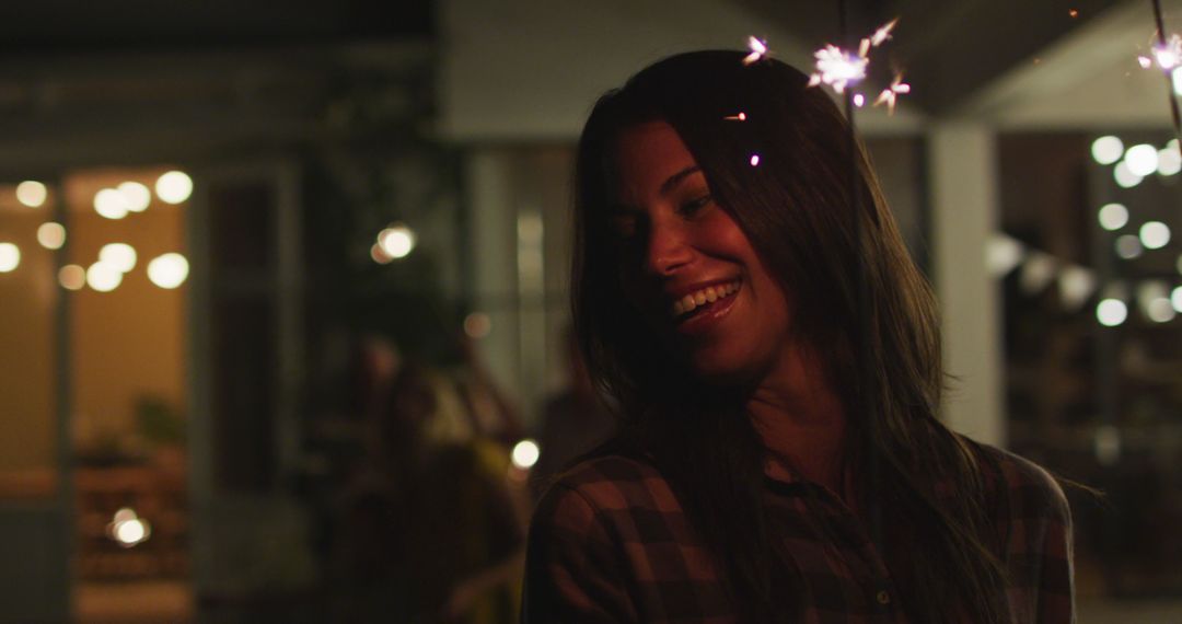 Smiling Woman Holding Sparklers at Nighttime Outdoor Party - Free Images, Stock Photos and Pictures on Pikwizard.com