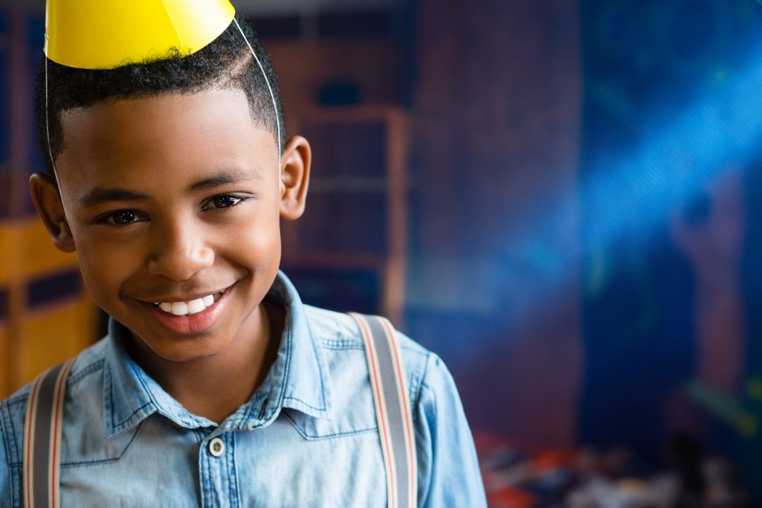 Smiling Boy Celebrating in Playroom with Party Hat