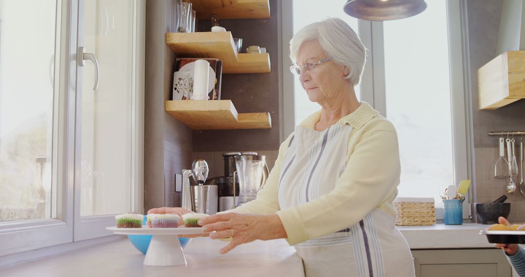 Senior Woman Arranging Cupcakes in Modern Kitchen - Free Images, Stock Photos and Pictures on Pikwizard.com