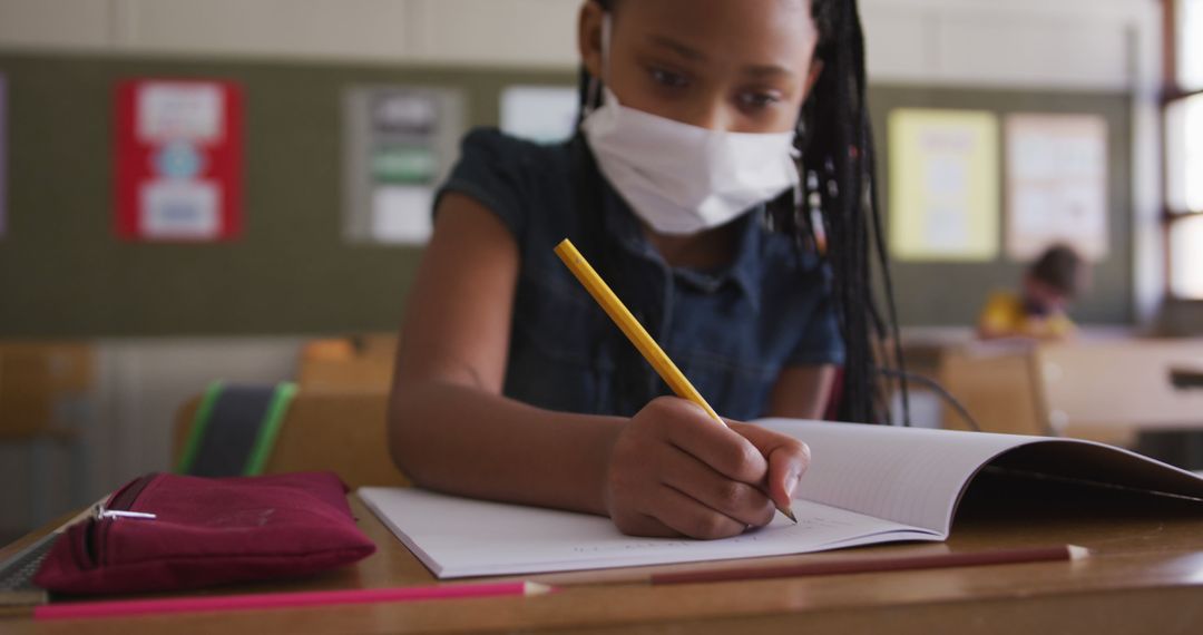 Young African American Girl Writing in Schoolwearing Mask - Free Images, Stock Photos and Pictures on Pikwizard.com