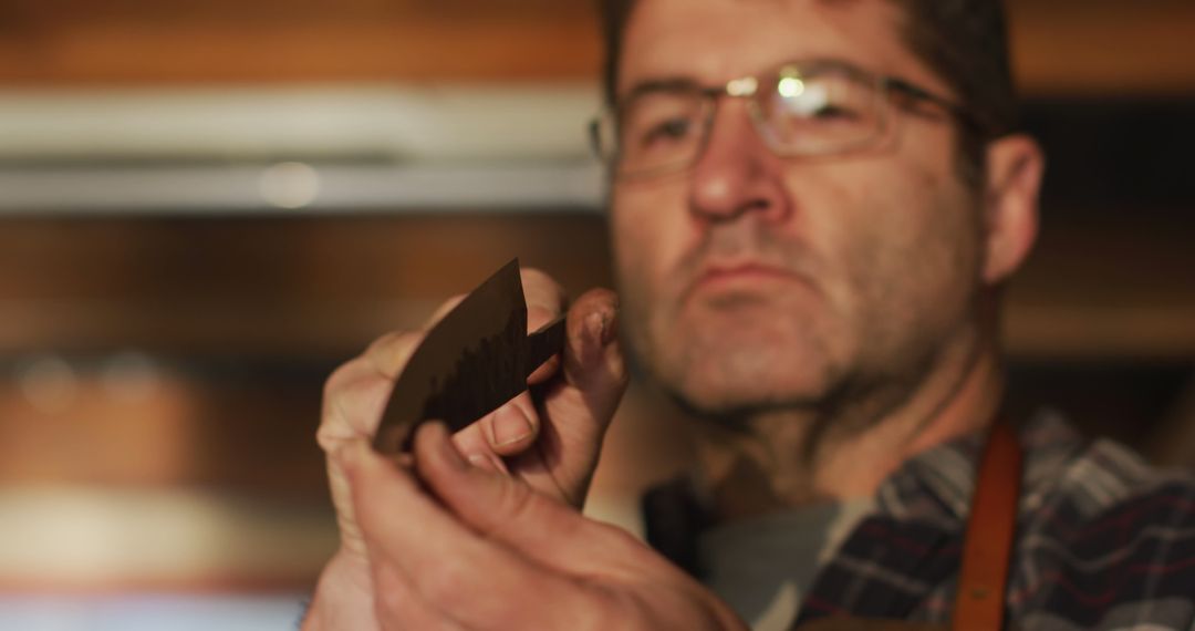 Focused Craftsman Holding and Inspecting Brown Leather Piece - Free Images, Stock Photos and Pictures on Pikwizard.com