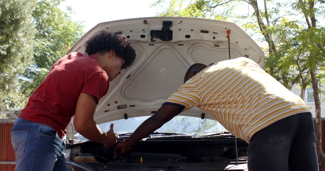 Friends Collaborating on Car Maintenance in Sunny Driveway