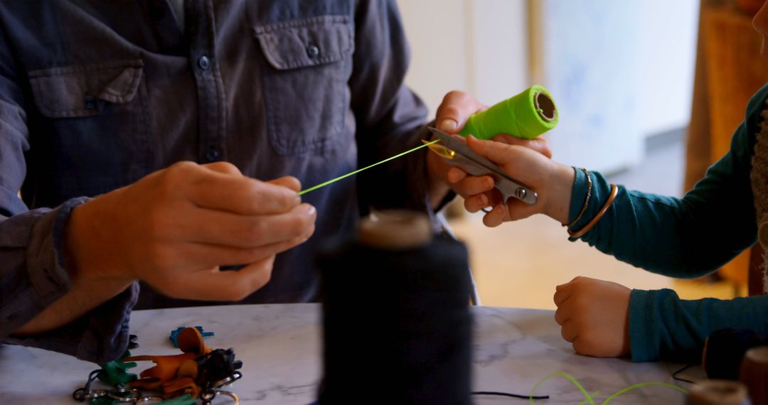 Father and Son Cutting Colorful Thread at Home Table