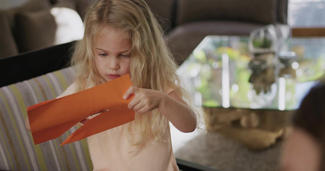 Blonde Girl Crafting with Orange Paper Cutting Strips, Concentrating on Hands-On Learning