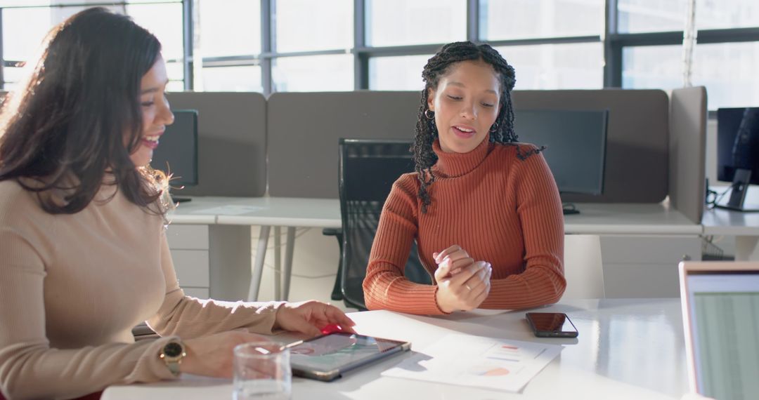 Female Colleagues Collaborating Over Tablet and Analytics Charts in Bright Modern Office