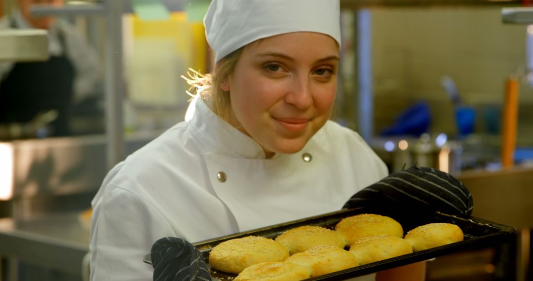 Female Chef Holding Tray of Freshly Baked Buns in Professional Kitchen - Free Images, Stock Photos and Pictures on Pikwizard.com