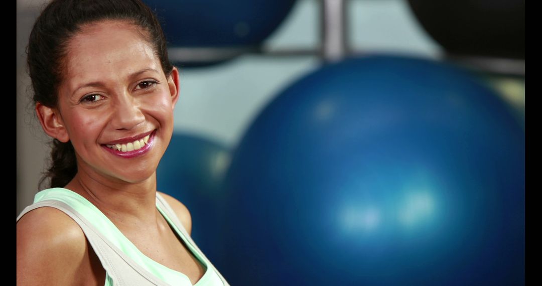 Smiling Woman in Gym Next to Exercise Balls - Free Images, Stock Photos and Pictures on Pikwizard.com