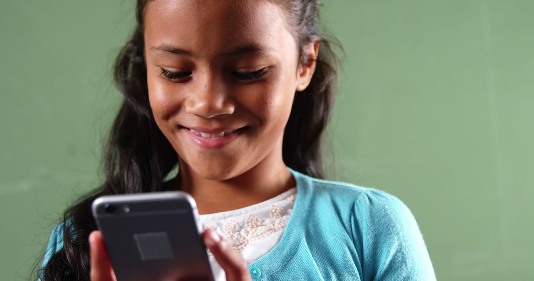 Smiling Girl Using Smartphone Against Green Background - Free Images, Stock Photos and Pictures on Pikwizard.com