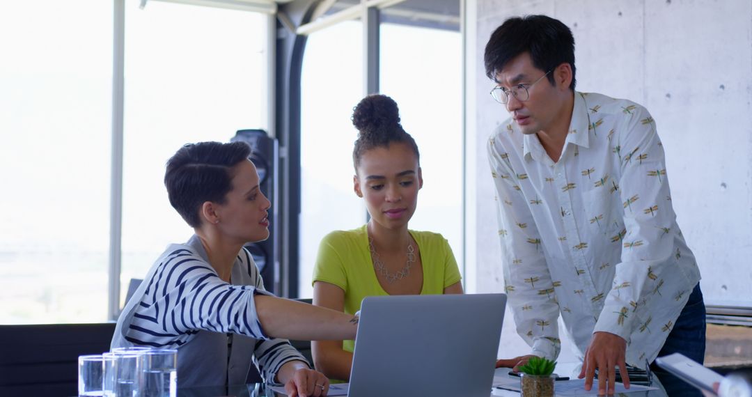 Diverse Business Team Collaborating Over Laptop in Open Workspace