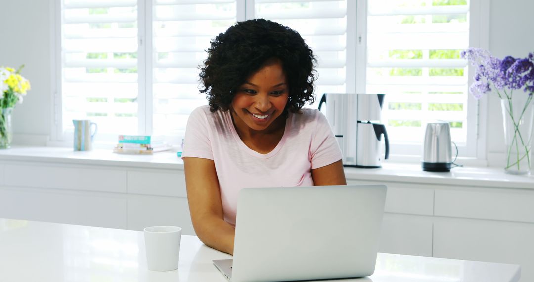 Smiling Woman Using Laptop in Modern Bright Kitchen - Free Images, Stock Photos and Pictures on Pikwizard.com