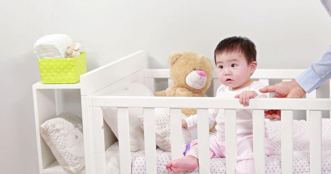 Father Watching Baby Standing in White Crib with Teddy Bear - Free Images, Stock Photos and Pictures on Pikwizard.com