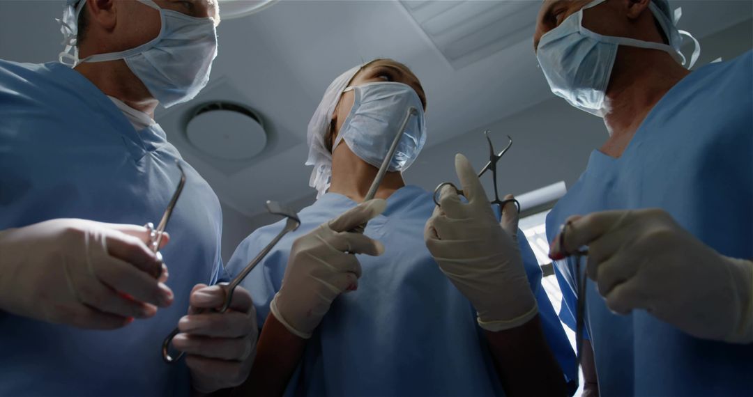 Surgical team performing operation in OR wearing masks and gloves holding forceps and retractors