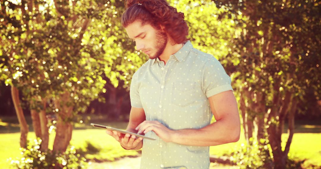 Young Man Using Tablet Outdoors on Sunny Day - Free Images, Stock Photos and Pictures on Pikwizard.com