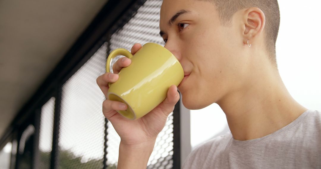 Youthful Person Drinking Hot Beverage from Yellow Mug Outdoors - Free Images, Stock Photos and Pictures on Pikwizard.com