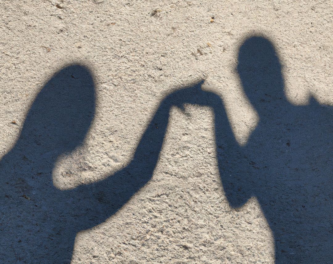 Silhouettes of Two People Touching Fingers on Sandy Ground - Free Images, Stock Photos and Pictures on Pikwizard.com