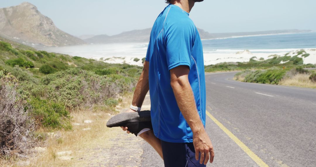 Man Stretching Leg Before Running on Coastal Road - Free Images, Stock Photos and Pictures on Pikwizard.com