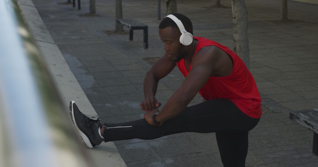 Man Stretching Outdoors with Headphones in Red Tank Top - Free Images, Stock Photos and Pictures on Pikwizard.com