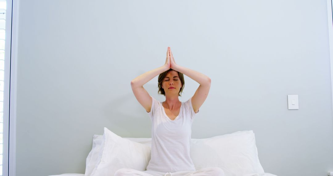 Young Woman Meditating on Bed with Eyes Closed and Hands Together - Free Images, Stock Photos and Pictures on Pikwizard.com