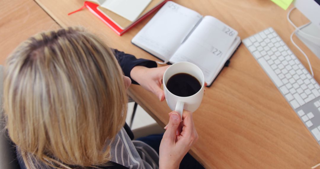 Woman Holding Coffee Cup While Planning in Office - Free Images, Stock Photos and Pictures on Pikwizard.com