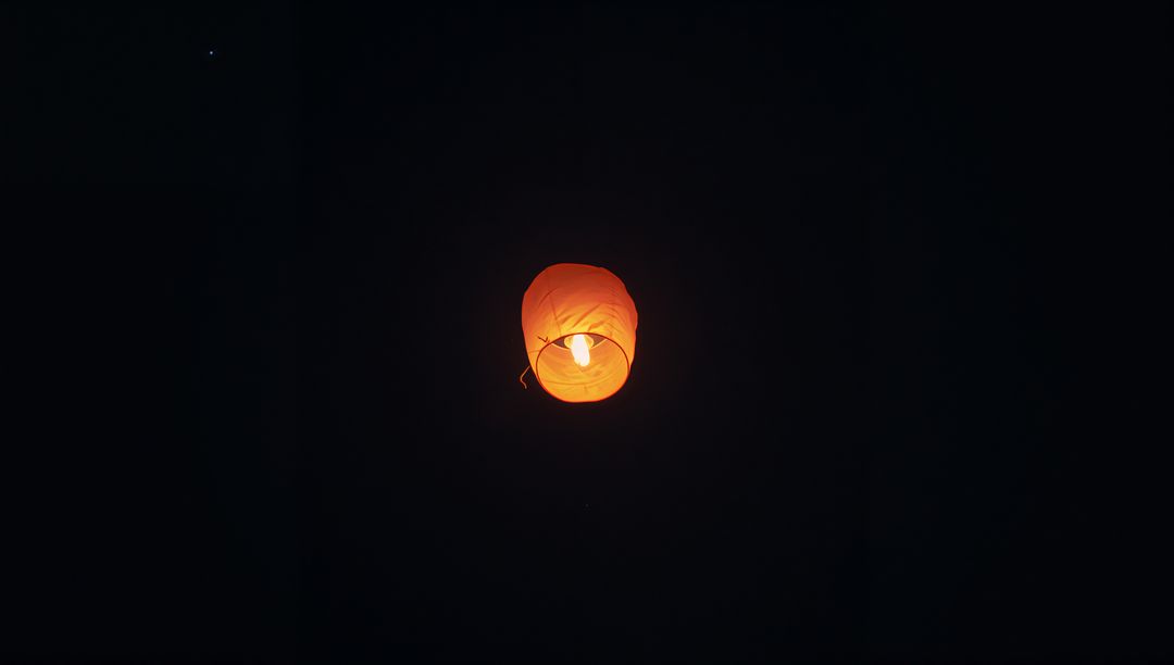 Tranquil Orange Sky Lantern Rising in Night Sky