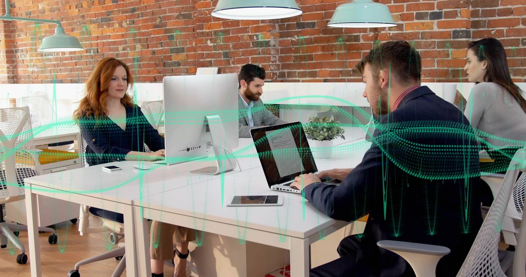 Business team collaborating in modern open-plan office with exposed brick and laptops