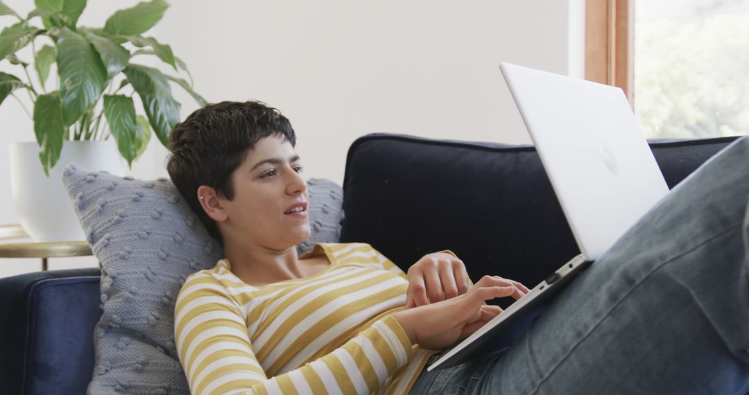 Relaxed Woman Using Laptop on Sofa in Bright Living Room - Free Images, Stock Photos and Pictures on Pikwizard.com