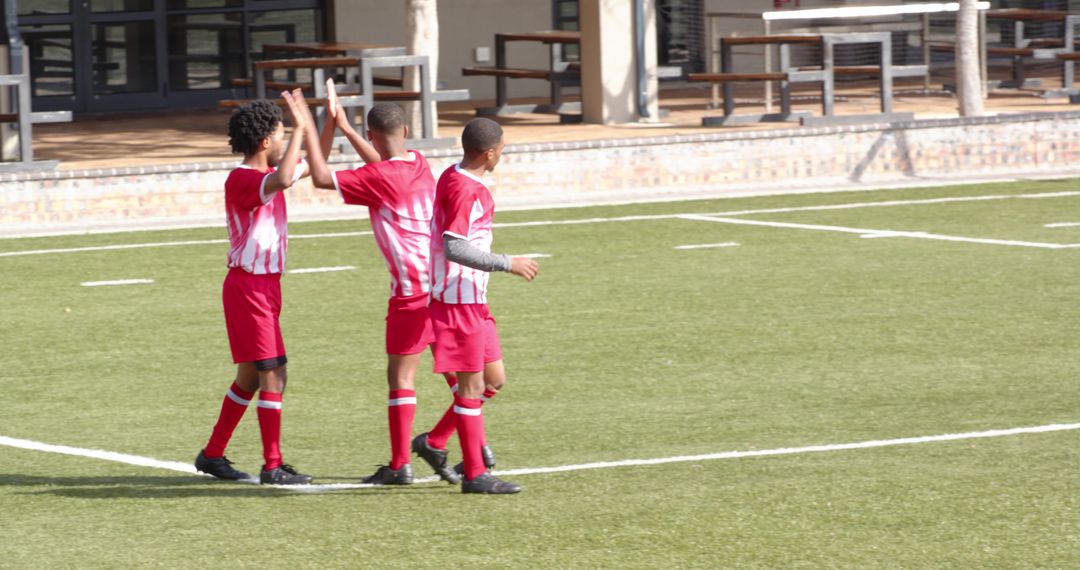 Young Soccer Players Celebrating on Field in Red Uniform