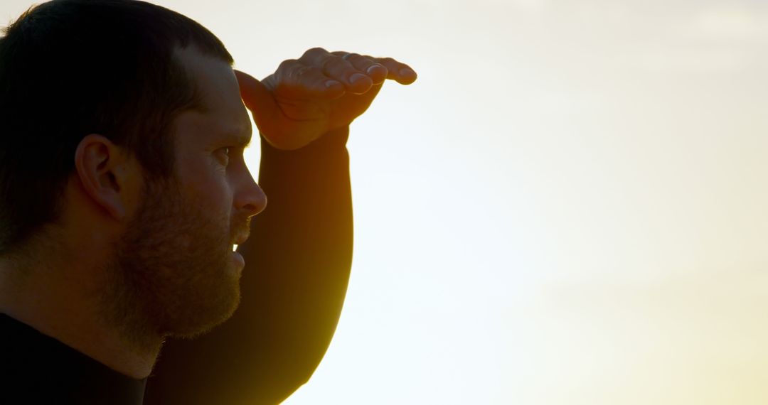 Surfer Scanning Horizon During Sunset for Waves in Wetsuit