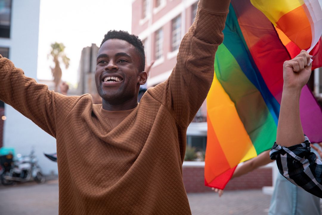 Smiling African American Man Holding Rainbow Flag at Demonstration - Free Images, Stock Photos and Pictures on Pikwizard.com