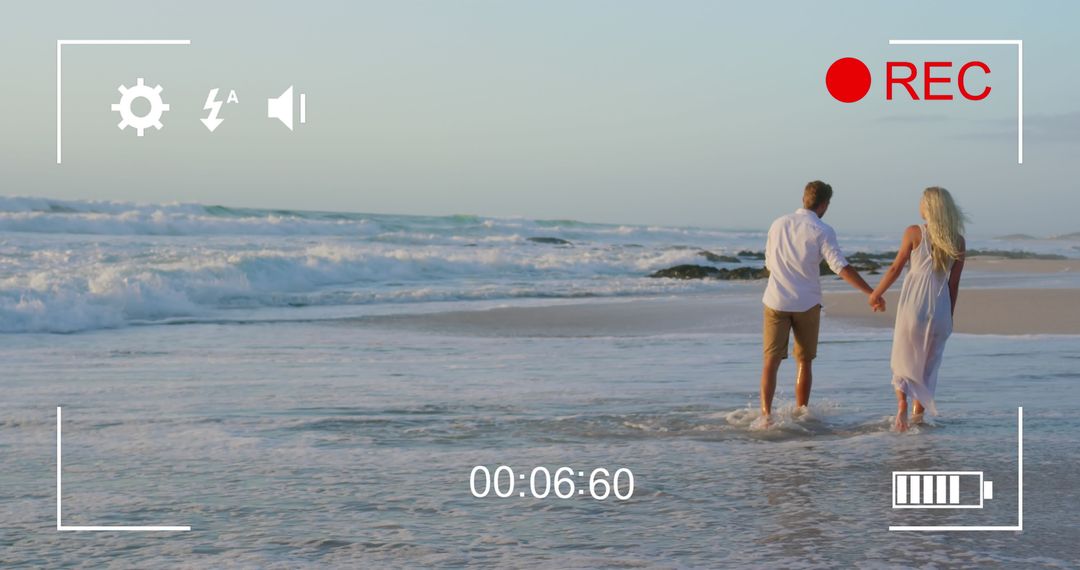 Young Couple Holding Hands on Ocean Shoreline Being Recorded