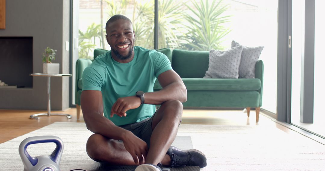 Smiling Man in Workout Clothes Relaxing at Home with Kettlebell
