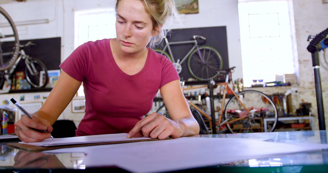 Female Bicycle Mechanic Writing Notes in Workshop - Free Images, Stock Photos and Pictures on Pikwizard.com