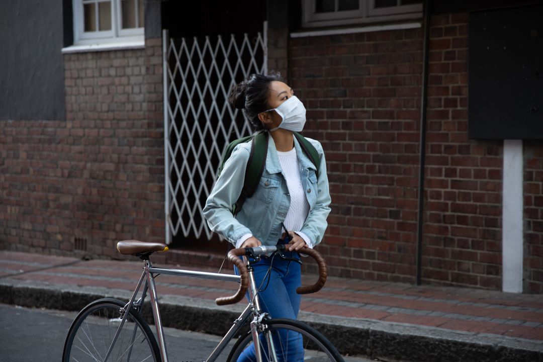 Young woman wearing face mask walking with her bicycle on the street - Free Images, Stock Photos and Pictures on Pikwizard.com