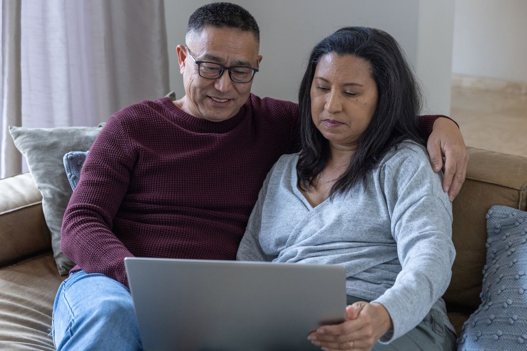 Senior Couple Relaxing on Sofa Using Laptop at Home