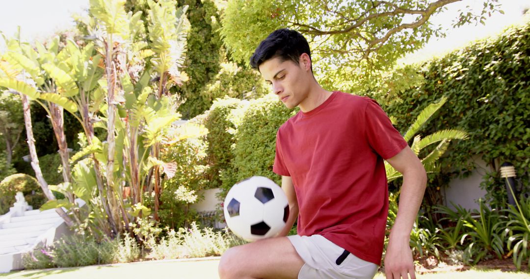Young Man Practicing Soccer Skills in Sunny Garden