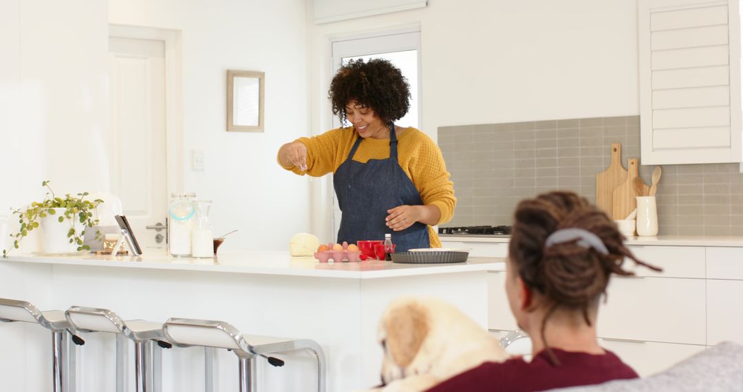Diverse couple baking at breakfast bar, woman cracking eggs in modern kitchen