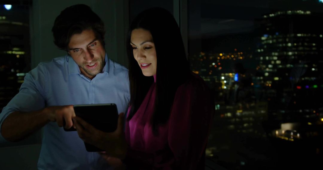 Professionals Collaborating on Tablet with City Skyline at Night