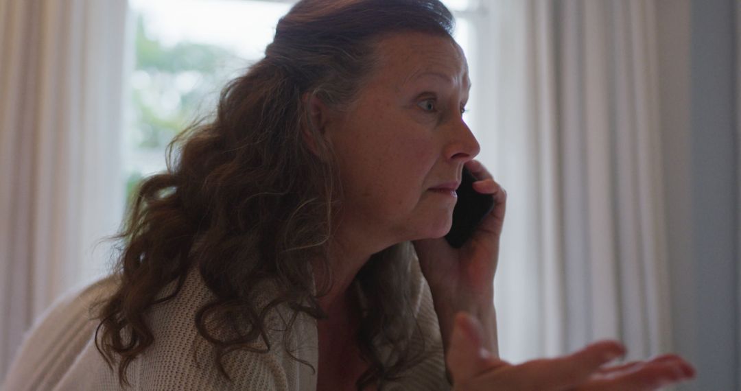 Concerned Middle-aged Woman Talking on Phone Indoors - Free Images, Stock Photos and Pictures on Pikwizard.com