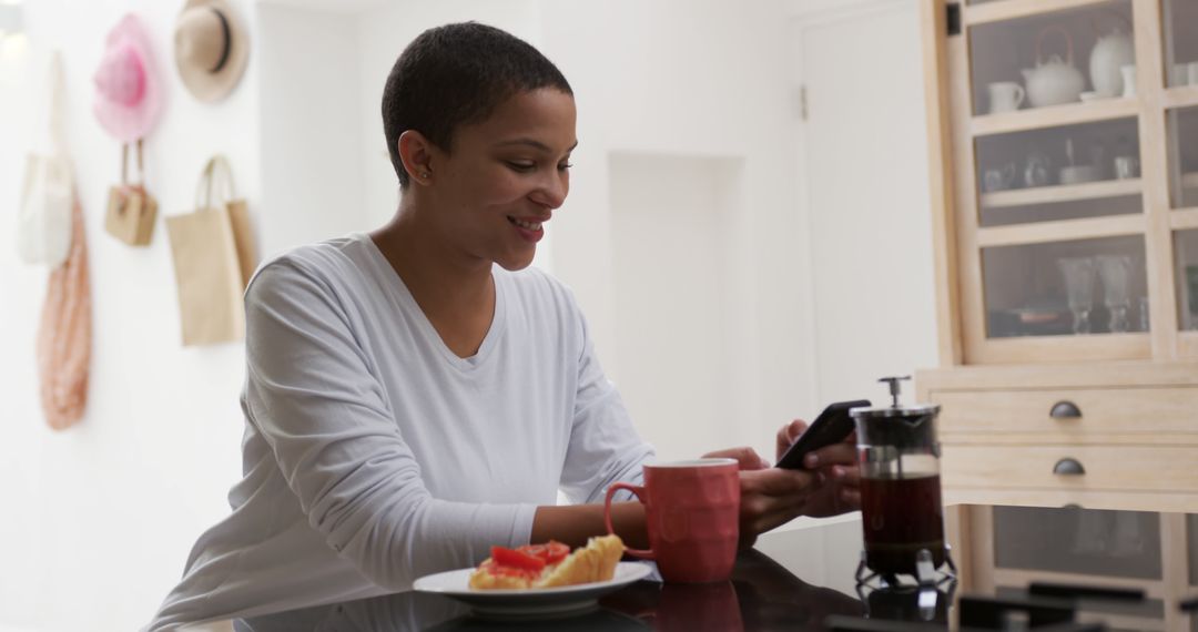 Smiling African American Woman Using Smartphone in Modern Kitchen - Free Images, Stock Photos and Pictures on Pikwizard.com