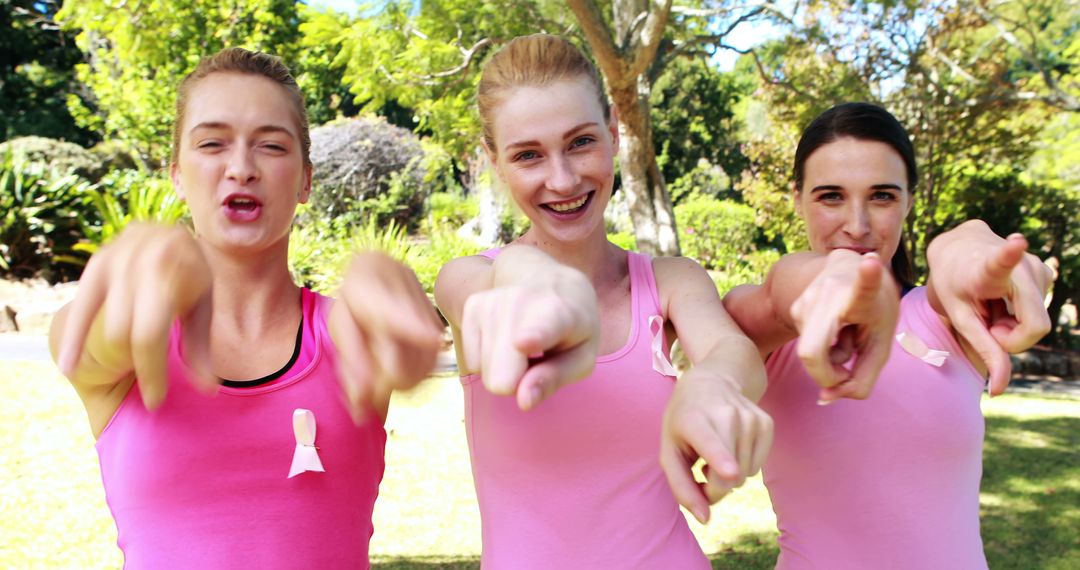 Group of Women Pointing and Smiling in Pink Shirts Outdoors - Free Images, Stock Photos and Pictures on Pikwizard.com