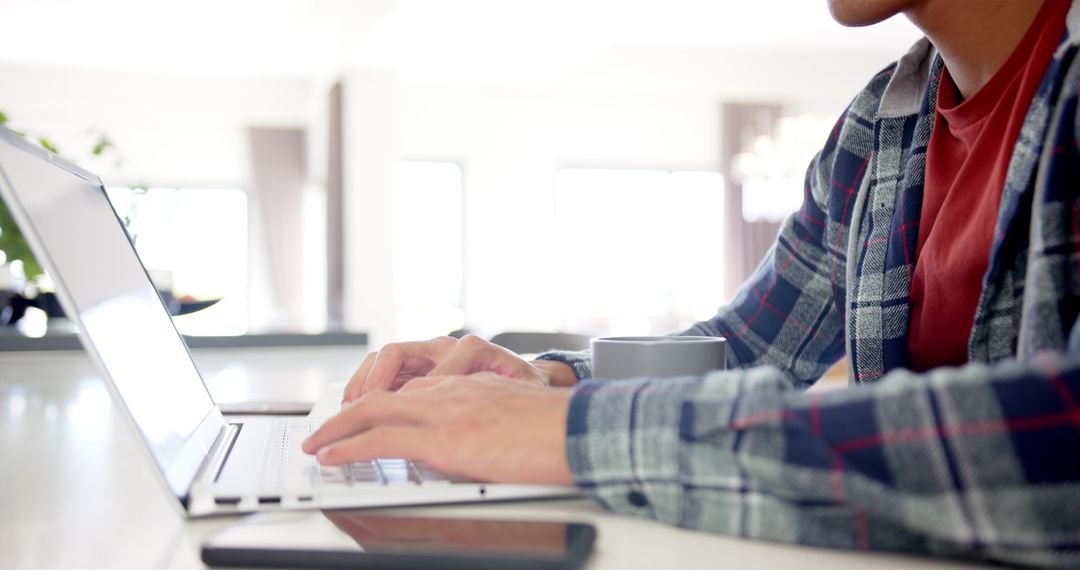 Man Working from Home Typing on Laptop with Coffee Mug Nearby