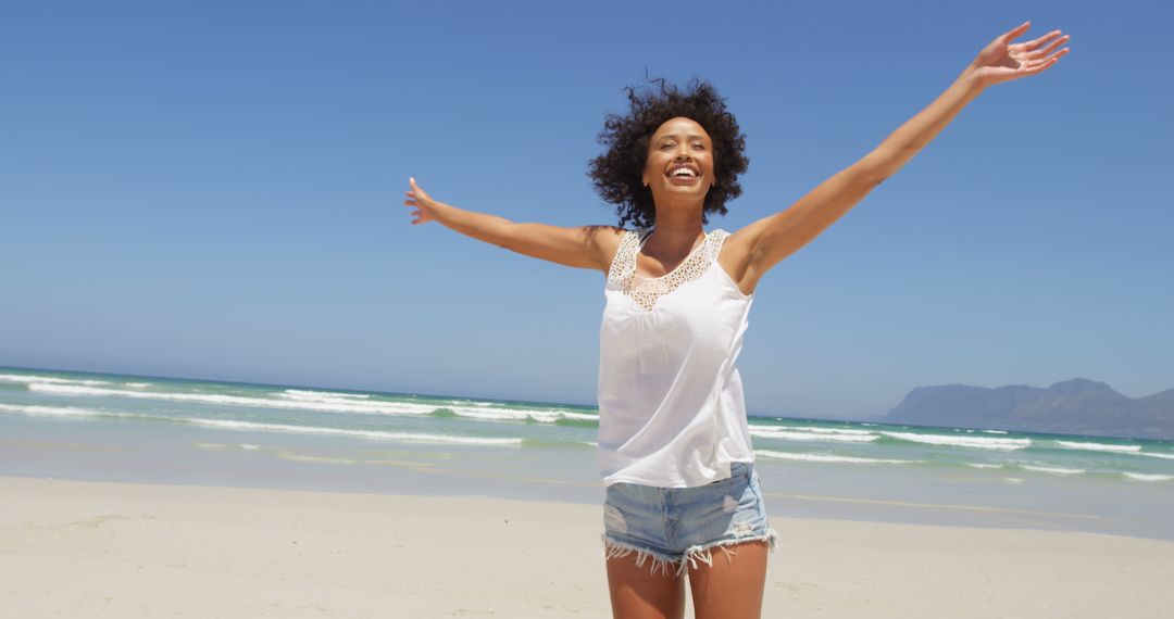 Joyful Woman with Outstretched Arms Enjoying Beach on Sunny Day - Free Images, Stock Photos and Pictures on Pikwizard.com