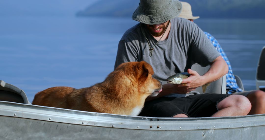 Man showing fish to dog while boating on lake - Free Images, Stock Photos and Pictures on Pikwizard.com